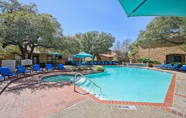 A pool area with a hot tub and lounge chairs.