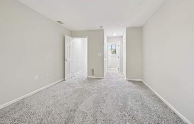 A master bedroom with carpeted floors and white walls.