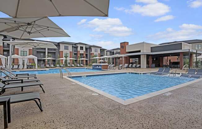 Luxurious pool area at 49 West's modern apartment complex, featuring cushioned lounge chairs and large umbrellas under a clear blue sky, conveying relaxation.
