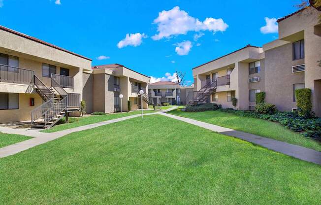 A sunny day at the apartment complex with green lawns and buildings on either side.