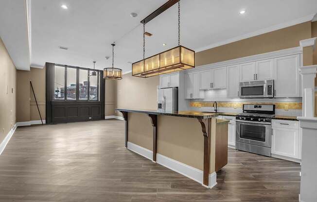 A modern kitchen with a dark wood floor and white cabinets at The Knights @ 506 Delaware Apartments, Buffalo, 14202