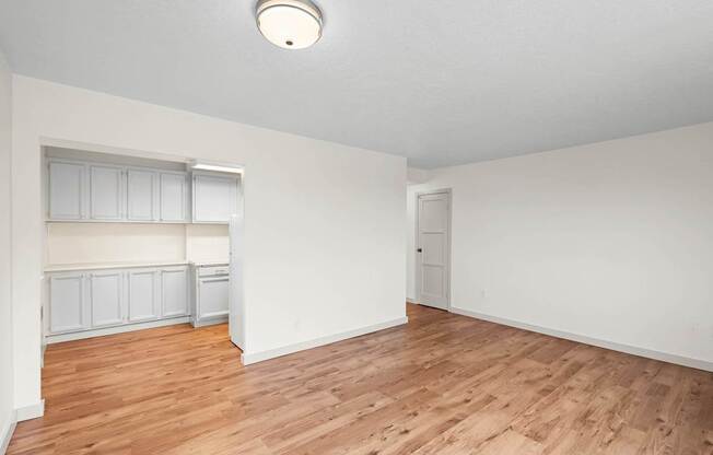 an empty living room with wood flooring and white walls