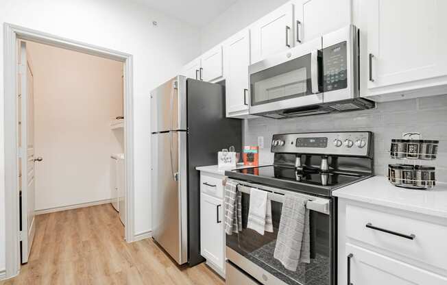 a kitchen with white cabinets and stainless steel appliances and a refrigerator
