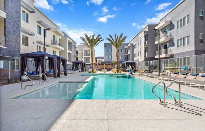 A swimming pool in a residential area surrounded by buildings and palm trees.