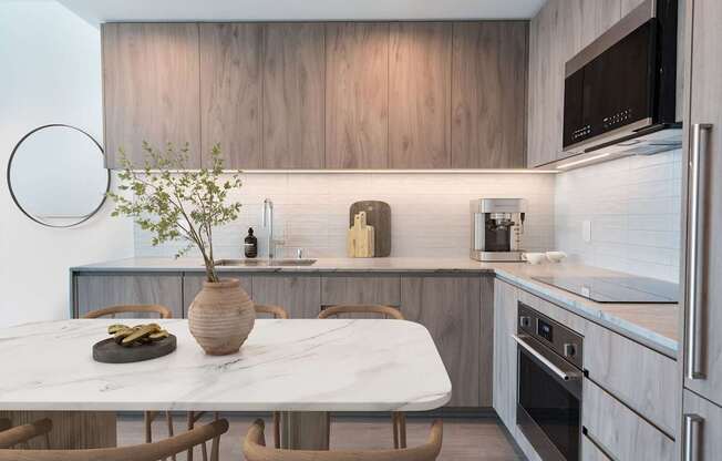 A kitchen with a marble table and wooden chairs.