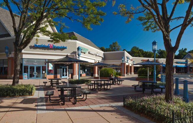 a patio outside of a shopping center with tables and umbrellas