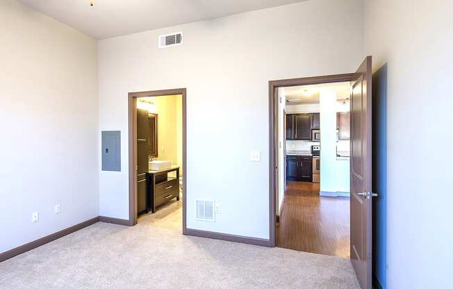 a bedroom with two doors and a kitchen in the background