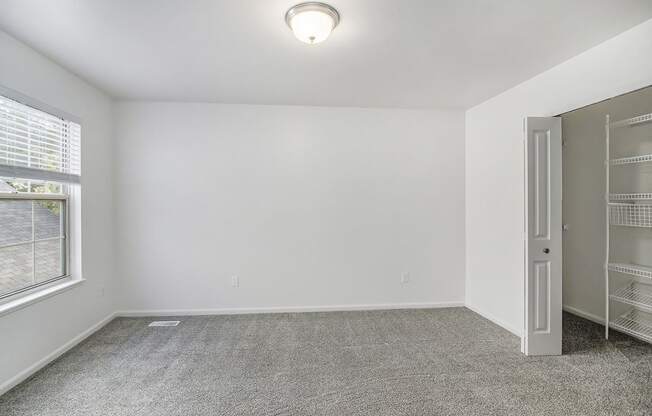 A bedroom with a grey carpet and a walk-in closet at Foxwood and The Hermitage, Portage, MI, 49024