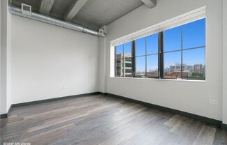 an empty living room with a large window and wood floors