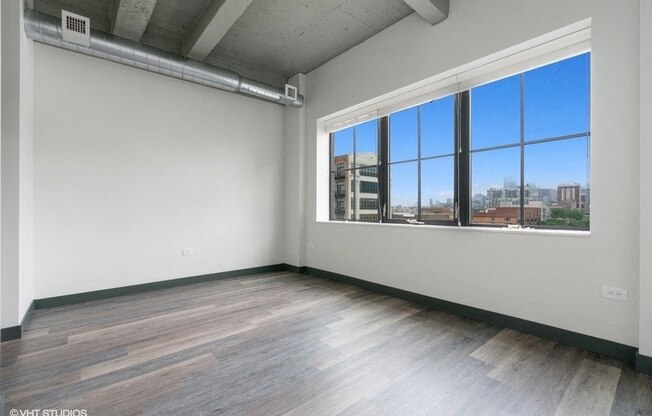 an empty living room with a large window and wood floors