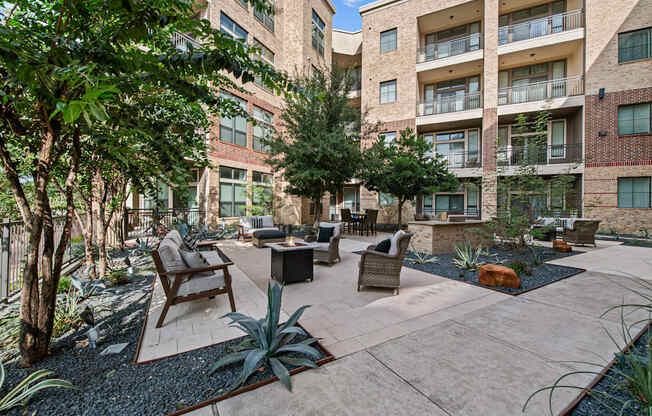 a courtyard with a seating area and trees in front of an apartment building