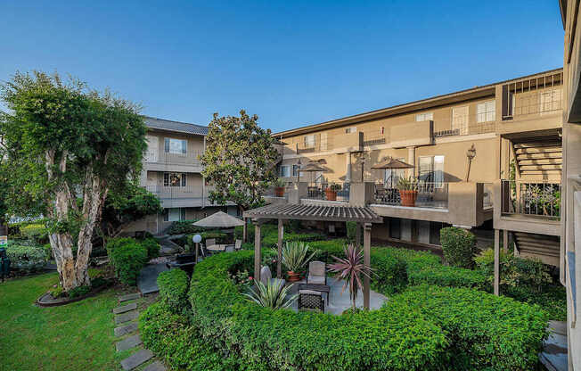 A courtyard with a tree, a bench, and a table surrounded by buildings.