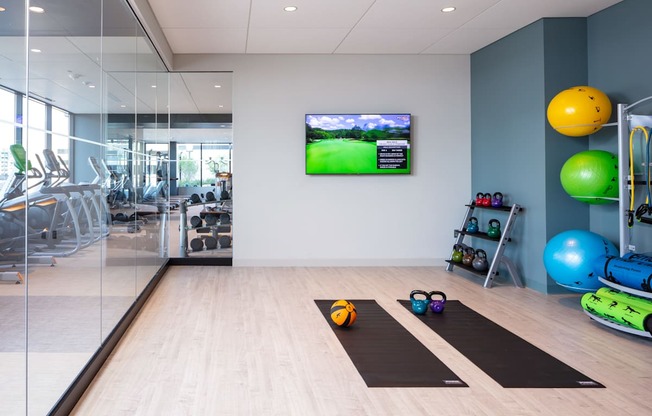A gym with exercise equipment and a TV screen showing a golf game.