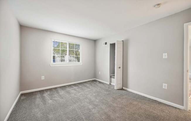 Empty room with white door and carpeted floor and window at ReNew Odenton