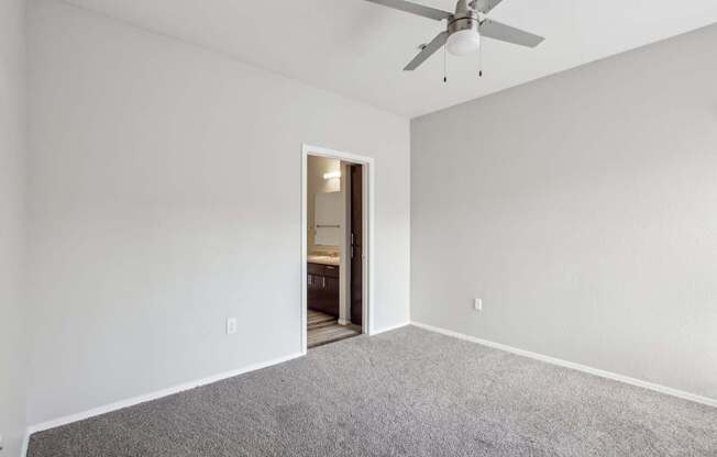 A room with a ceiling fan and carpeted floor.