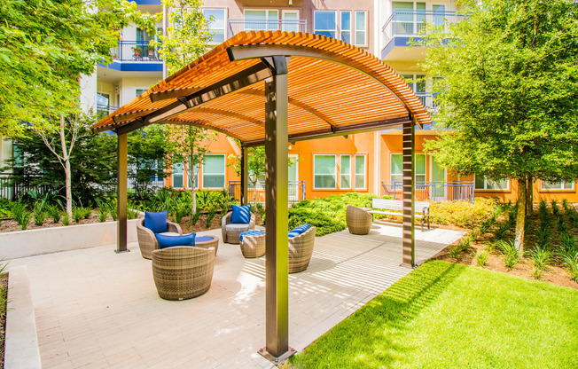 a patio with chairs and a pergola in front of an apartment building at South Side Flats, Dallas, TX, 75215