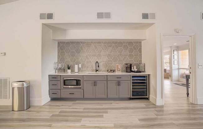 A modern kitchen with a grey backsplash and a trash can.