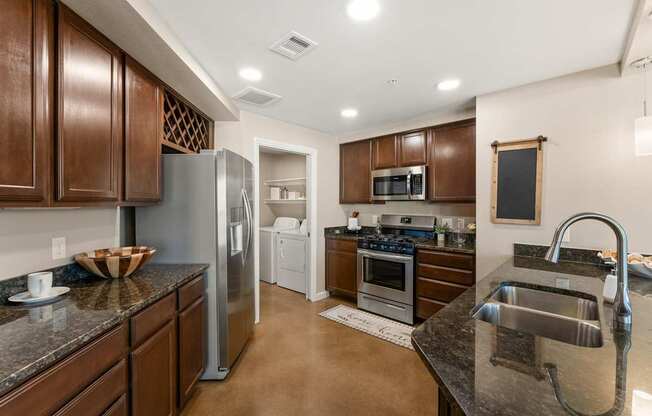 A kitchen with brown cabinets and a black counter top. at Bridge at Heritage Woods, Austin, Texas