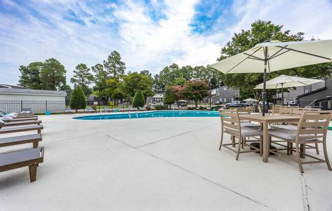 our apartments have a large pool and patio with tables and chairs