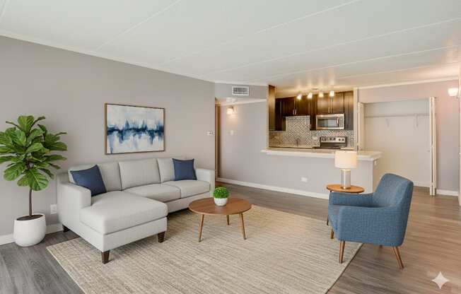 A living room with a white couch, a blue chair, and a painting on the wall.