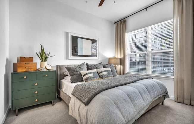 a bedroom with a large window and ceiling fan