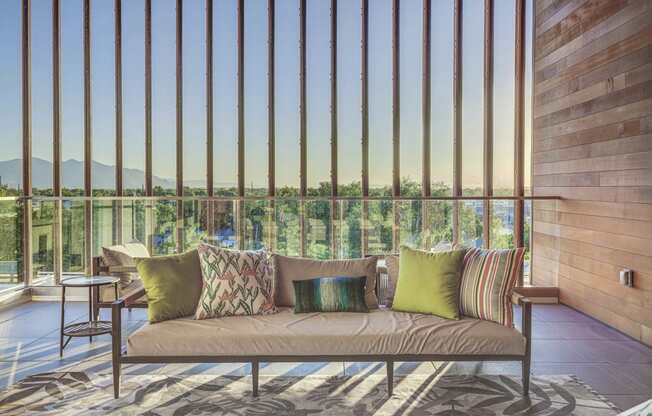 a couch with pillows in front of a window with vertical blinds