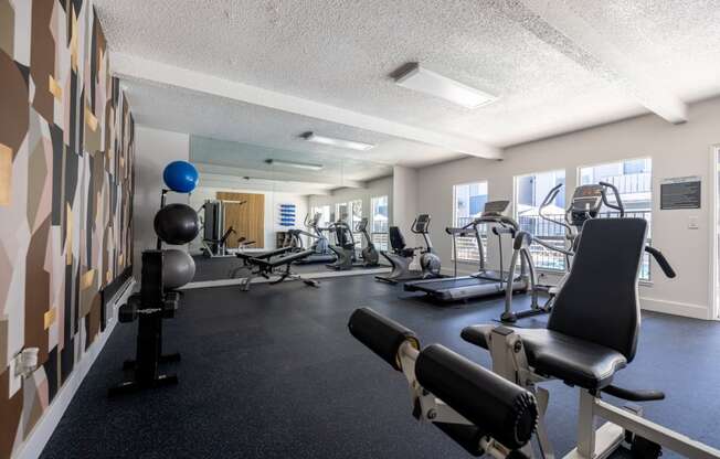 a gym with weights and other exercise equipments in a room with a large window at Campbell West Apartments, California 95008