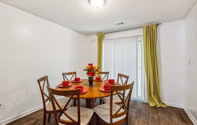 a dining room with a table and chairs and a window with yellow curtains