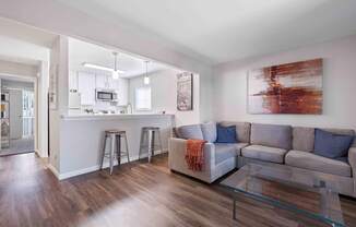 A modern living room with a grey couch and a glass coffee table.