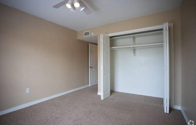 an empty bedroom with a closet and a ceiling fan