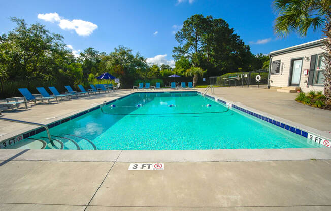 a swimming pool with blue chairs around it in front of a building