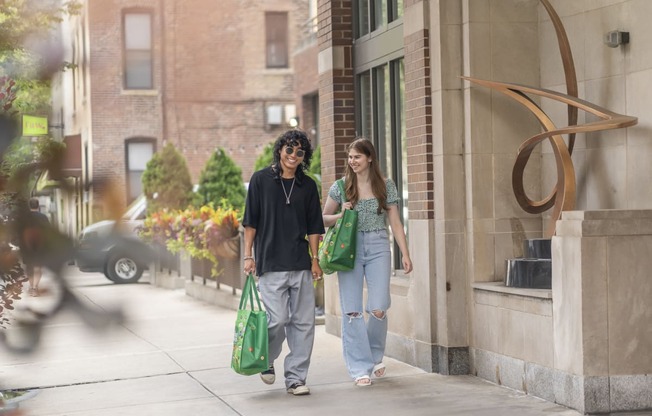 a man and a woman walking down the street with green bags