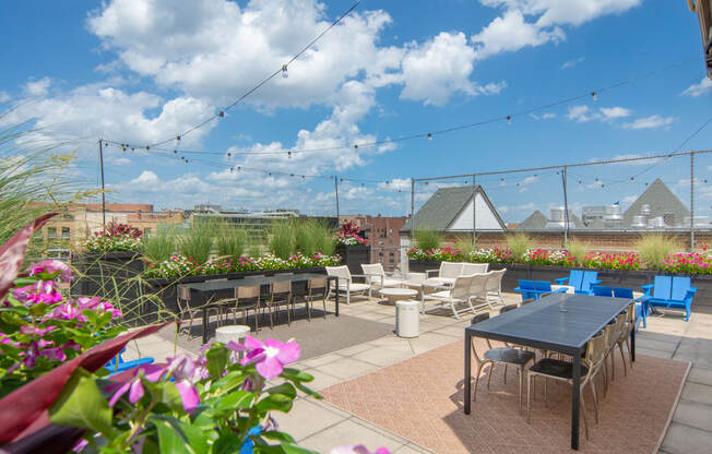 a rooftop patio with tables and chairs and flowers