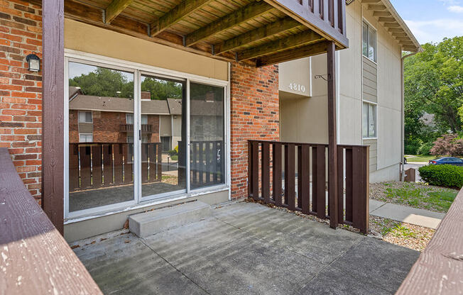 a porch in front of a brick house with a sliding glass door