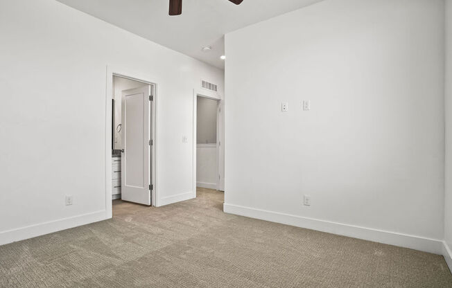 a living room with white walls and a door to a bathroom  at Aero Luxury Townhomes in Layton, Utah