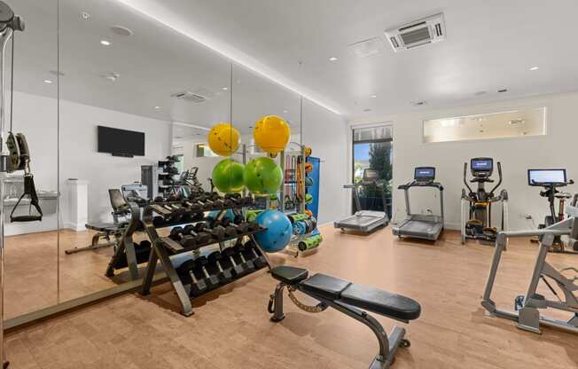 a gym with cardio equipment and weights on a wooden floor