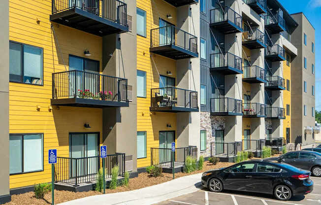 an apartment with balconies and cars parked in front of them. Circle Pines, MN Lexington Lofts