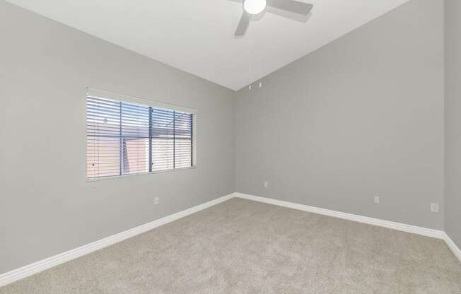 an empty room with a window and a ceiling fan