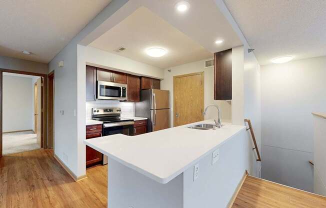 A kitchen with a white counter top and wooden floors.