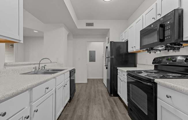 A kitchen with black appliances and white cabinets.