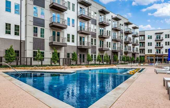 A large swimming pool is surrounded by apartment buildings.