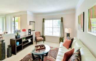 Living room with couch table and chair with painting on wall and window