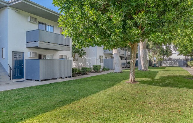 an apartment building with a lawn and trees in front of it at BLVD Apartments LLC, Tarzana, CA