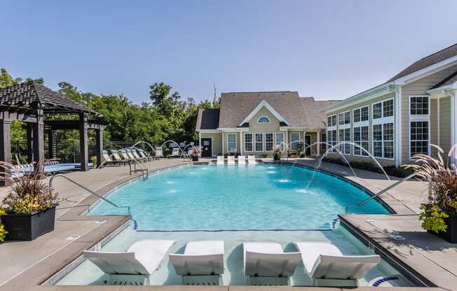 our resort style pool is surrounded by white chairs and a house with a swimming pool