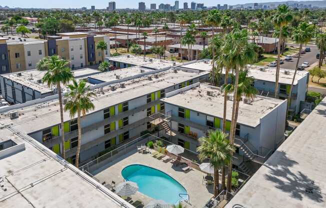 an aerial view of an apartment complex with a pool and palm trees