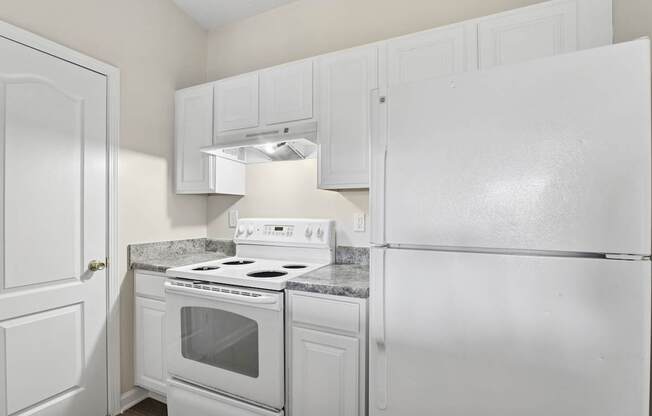 A white kitchen with a stove and refrigerator.