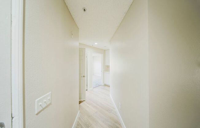 A long, narrow hallway with white walls and a light switch.