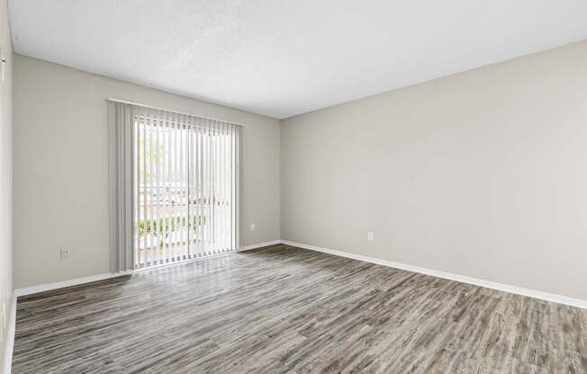 A room with wooden flooring and a sliding glass door.