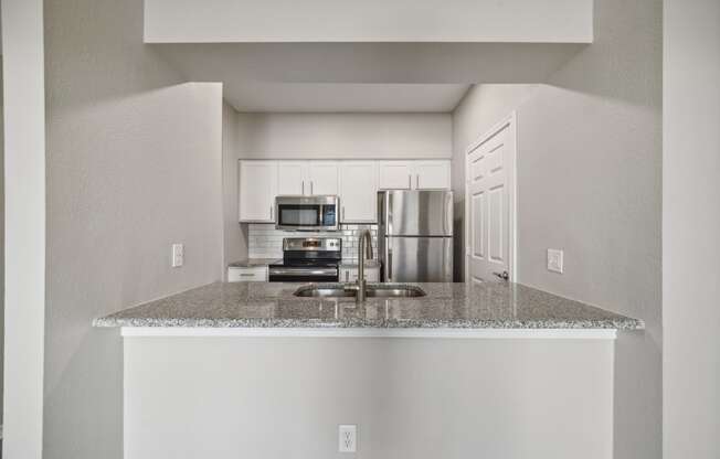 a kitchen with white cabinets and stainless appliances