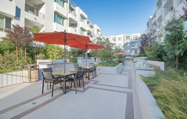 A patio with a table and chairs under a red umbrella at Woodley Sara Apartment, Van Nuys